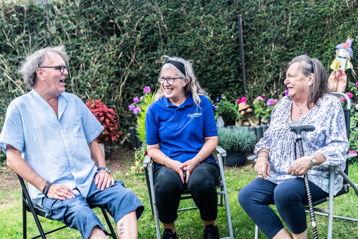 Peter and Anita sat in their garden smiling with a LiveWest colleague.