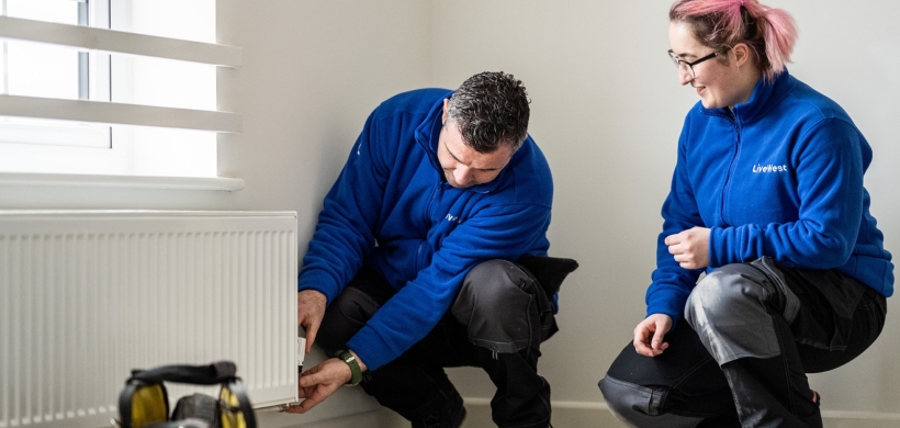 Two LiveWest colleagues carrying out a repair to a radiator in a customer home. 