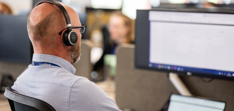 A LiveWest colleague speaking on the phone with a headset. 