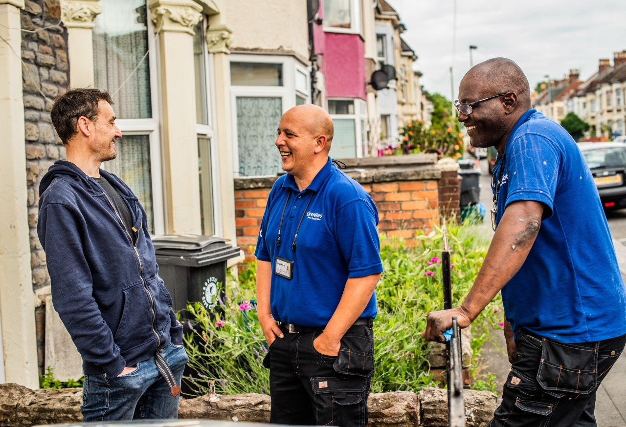 LiveWest colleagues smiling and talking with customer outside house.