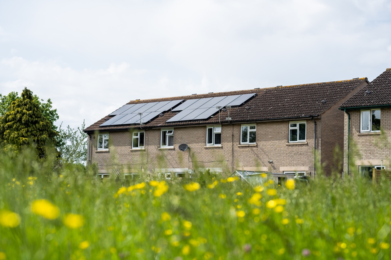 Image of a home with solar panels in the background of a field.