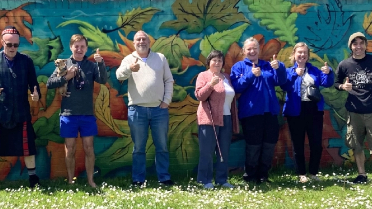 Residents and colleagues in front of wall with art on. 