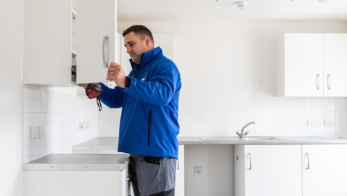 LiveWest colleague fixing kitchen cupboard door. 