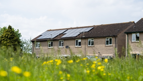 Image of a home with solar panels in the background of a field.