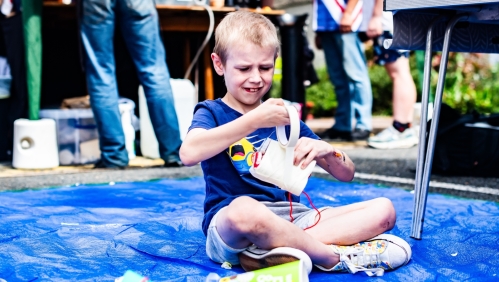 A boy sat on the floor making something with materials. 