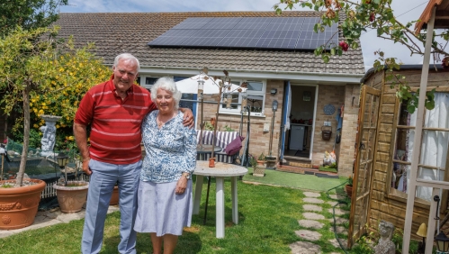 Our customers, James and Catherine, stood in their garden outside their bungalow.